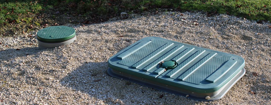 Assainissement individuel : trappes d’accès visibles sur une zone gravillonnée pour fosse septique ou micro-station.
