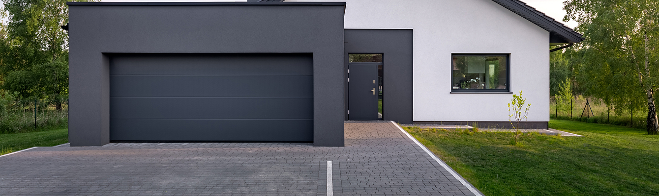Entrée de maison moderne avec cour en pavés gris et allée menant au garage, entreprise de terrassement MLD TP