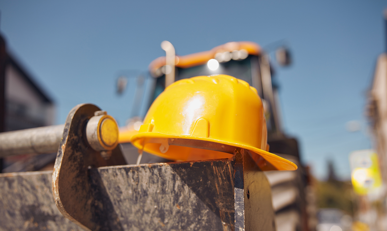 Terrain pétanque maison fraîchement réalisé, bande rectangulaire en gravier rouge bordée de traverses bois, terre préparée autour et maisons au fond.
